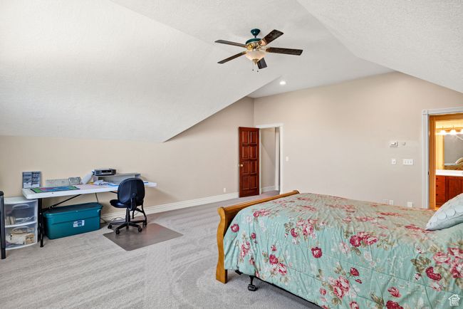 Bedroom featuring vaulted ceiling, carpet, a ceiling fan, a textured ceiling, and an office area | Image 53