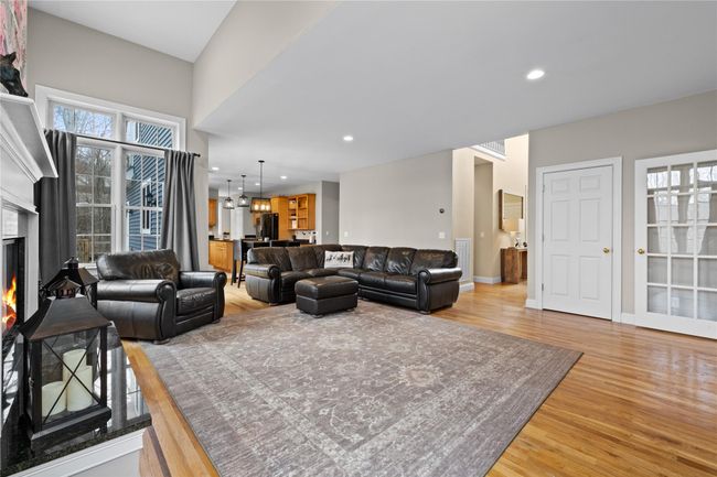 Living room featuring light wood finished floors, baseboards, a warm lit fireplace, and recessed lighting | Image 8
