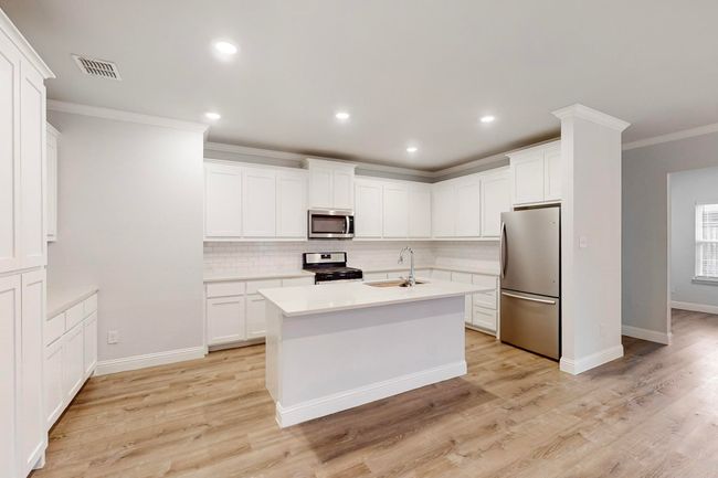 Kitchen with white cabinetry, stainless steel appliances, crown molding, and sink | Image 5