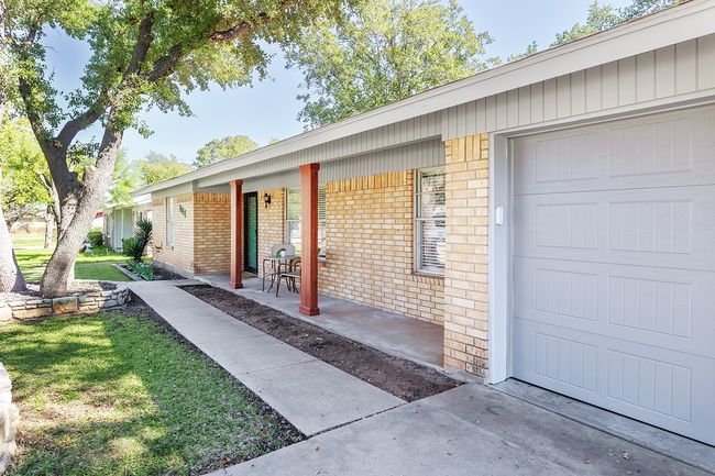 Doorway to property with a yard, brick siding, a garage, and covered porch | Image 38