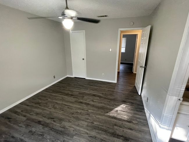 Unfurnished bedroom with a textured ceiling, dark wood-type flooring, and ceiling fan | Image 11