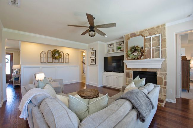Living area featuring crown molding, a ceiling fan, stairs, and visible vents | Image 14