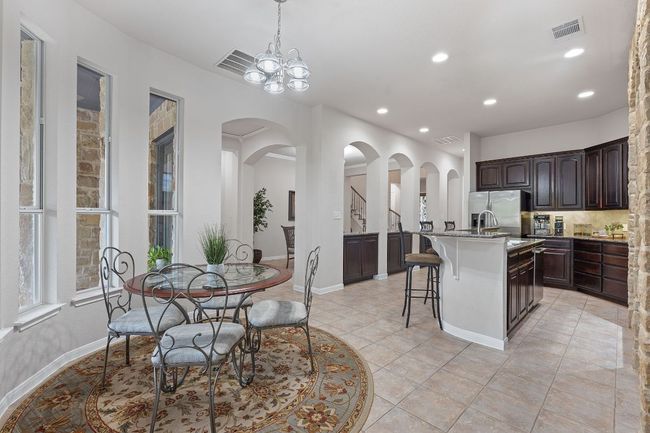 Kitchen with a breakfast bar, stainless steel fridge with ice dispenser, dark brown cabinets, recessed lighting, and light tile patterned floors | Image 8