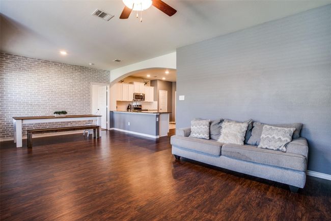 Living room featuring brick wall, ceiling fan, and dark hardwood / wood-style floors | Image 6