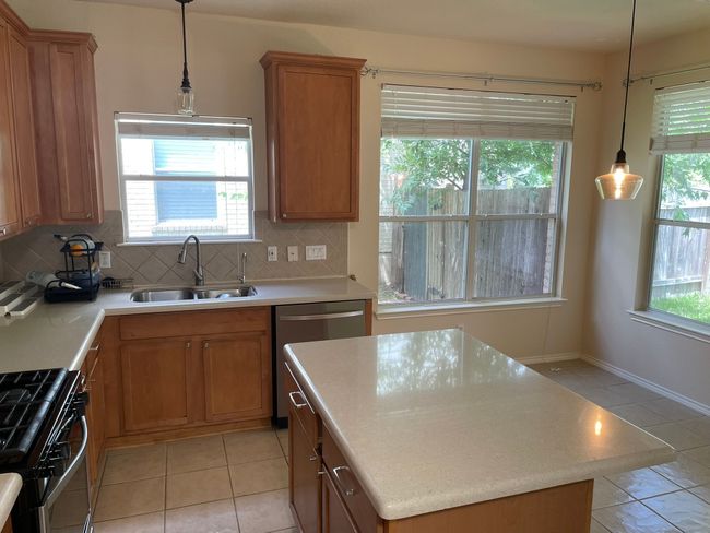 Kitchen with gas range, dishwasher, tasteful backsplash, light tile patterned floors, and light countertops | Image 4