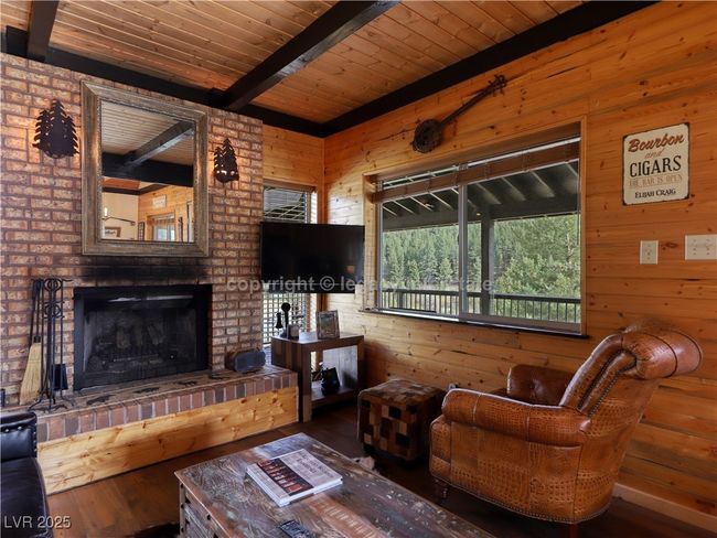 Living room featuring wood walls, beam ceiling, a fireplace, wood ceiling, and hardwood / wood-style flooring | Image 9