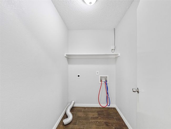 Laundry room featuring hookup for an electric dryer, wood finished floors, washer hookup, a textured ceiling, and baseboards | Image 6
