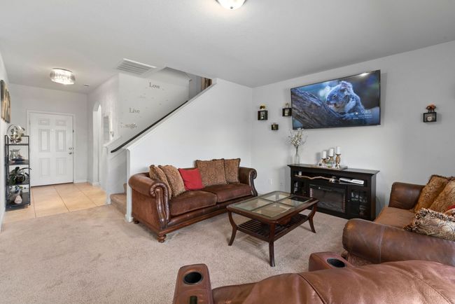 Living room with light tile patterned flooring, stairway, visible vents, and light carpet | Image 15