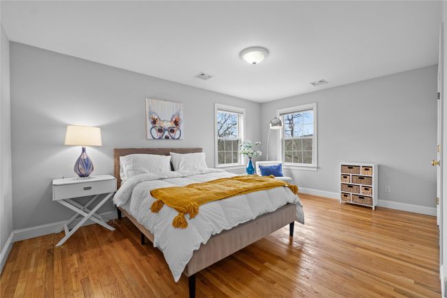 Bedroom featuring light wood finished floors, baseboards, and visible vents | Image 18