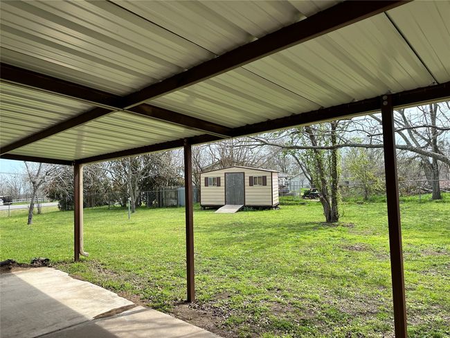 View of yard featuring a storage unit, a fenced backyard, an outdoor structure, and a patio area | Image 12