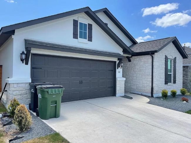 Single story home with stone siding, driveway, a garage, and a shingled roof | Image 4