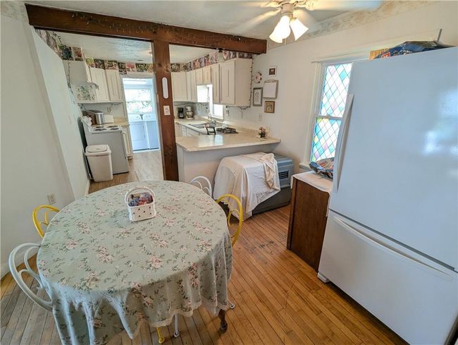 Kitchen with light wood-style flooring, white appliances, ceiling fan, light countertops, and washer / dryer | Image 16