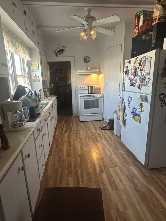 Kitchen featuring stove, white cabinetry, exhaust hood, hardwood / wood-style flooring, and refrigerator | Image 12