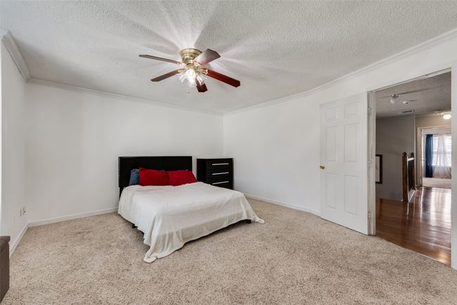Bedroom featuring crown molding, a textured ceiling, carpet flooring, and a ceiling fan | Image 20