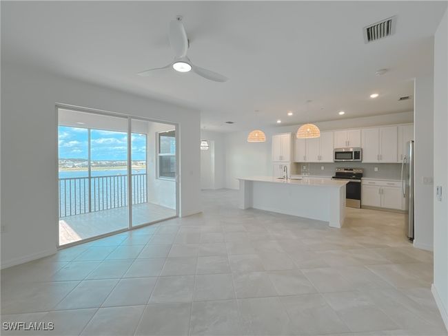 Kitchen featuring appliances with stainless steel finishes, a sink, light countertops, a kitchen island with sink, and white cabinetry | Image 10