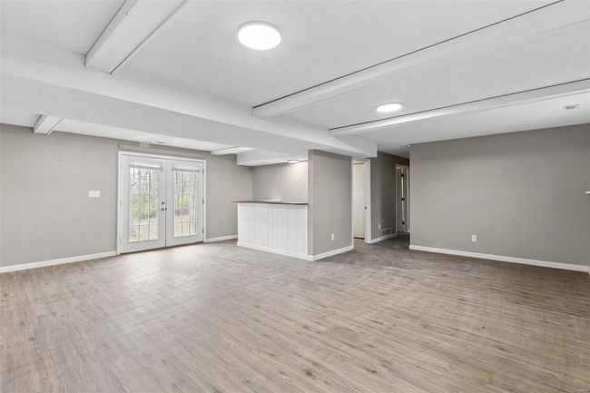 Basement featuring baseboards, visible vents, french doors, and light wood-type flooring | Image 25