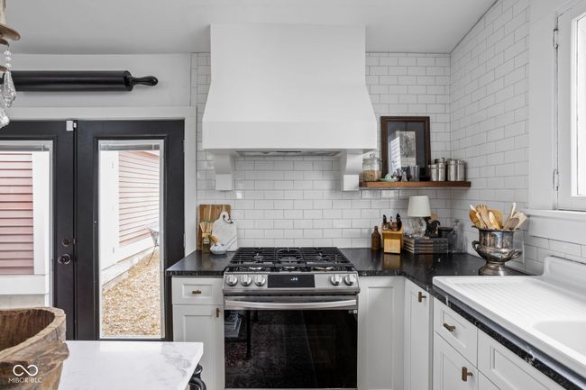 kitchen with stainless steel range with gas cooktop, custom exhaust hood, decorative backsplash, and white cabinets | Image 17