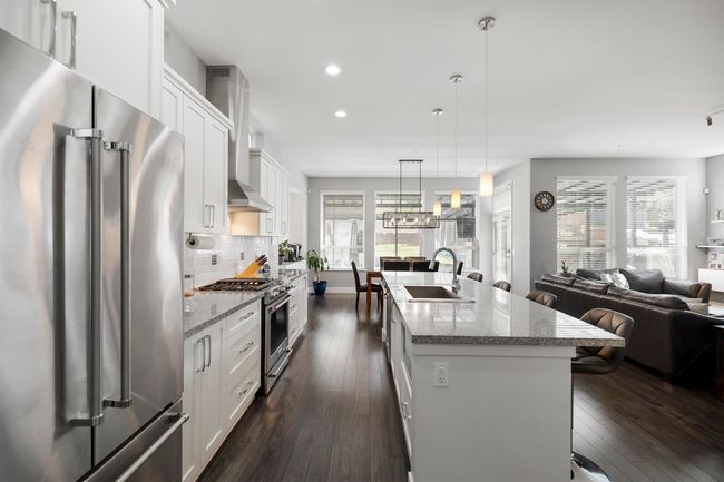 Kitchen with premium appliances, a sink, white cabinetry, tasteful backsplash, and open floor plan | Image 12
