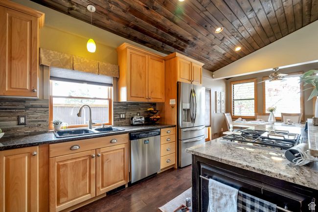 Kitchen featuring a sink, dark wood-style flooring, decorative backsplash, stainless steel appliances, and wood ceiling | Image 8