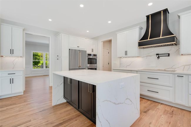 Kitchen with wall chimney exhaust hood, a sink, high end stove, light wood-type flooring, and freestanding refrigerator | Image 11