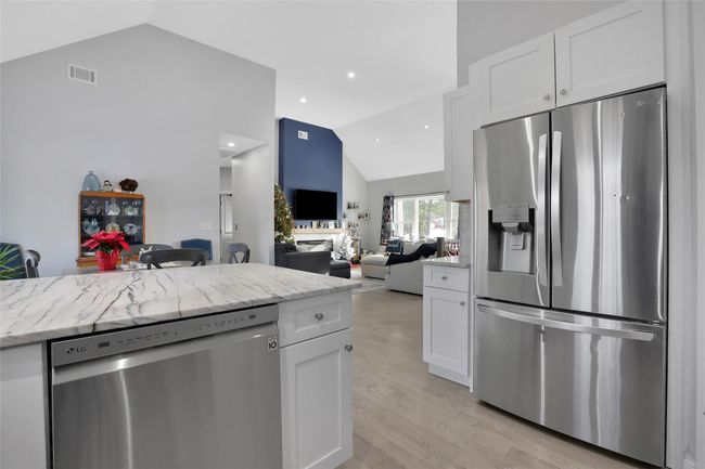 Kitchen with appliances with stainless steel finishes, white cabinetry, lofted ceiling, and light stone counters | Image 8