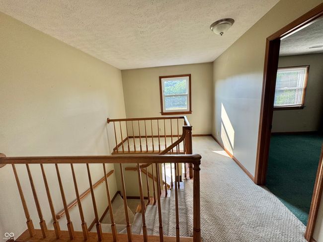 stairs featuring carpet, a textured ceiling, healthy amount of natural light, and baseboards | Image 56