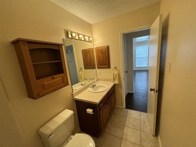 Bathroom featuring a textured ceiling, vanity, toilet, and tile flooring | Image 22