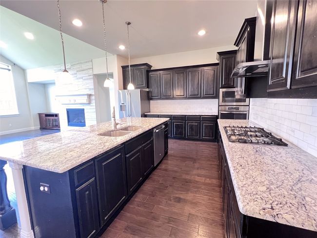 Kitchen featuring appliances with stainless steel finishes, dark wood finished floors, a center island with sink, decorative backsplash, and recessed lighting | Image 16