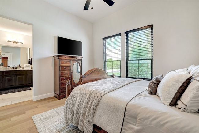 Bedroom with light wood floors, connected bathroom, and ceiling fan | Image 20