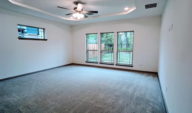Unfurnished room with a tray ceiling, visible vents, baseboards, carpet flooring, and ceiling fan | Image 20