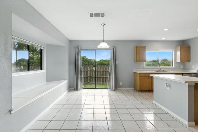 Kitchen featuring light countertops, healthy amount of natural light, light tile patterned floors, decorative light fixtures, and recessed lighting. Taken from the living room. | Image 5