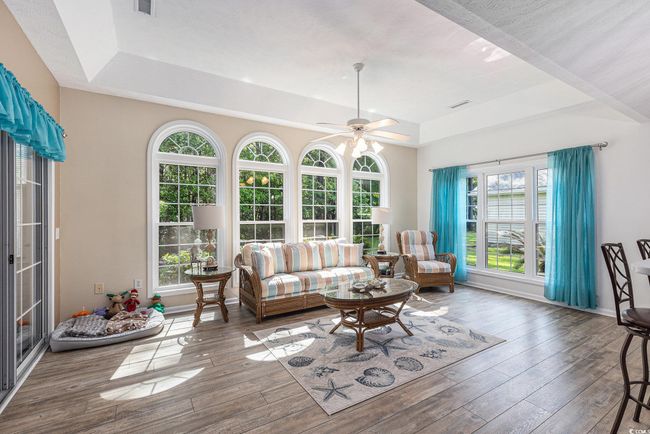 Living room featuring a raised ceiling, plenty of natural light, hardwood / wood-style floors, and ceiling fan | Image 15