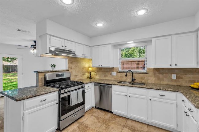 This kitchen has freshly painted cabinets and knobs, new stove and dishwasher and a vent. | Image 13