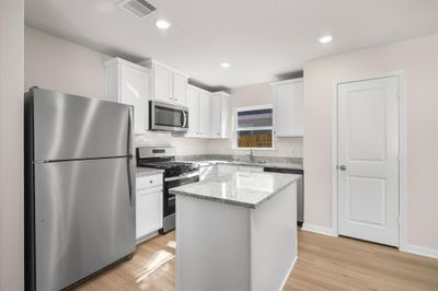 Stainless Steel appliances with white cabinets, along with a breakfast bar. | Image 2