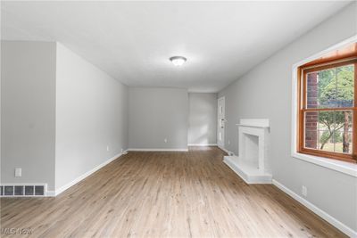 Unfurnished living room featuring a brick fireplace and light hardwood / wood-style floors | Image 3