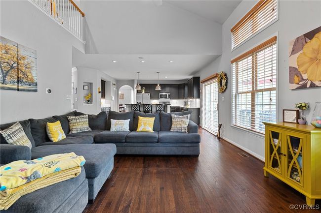 Living room featuring dark wood-style floors, high vaulted ceiling, baseboards, and visible vents | Image 19