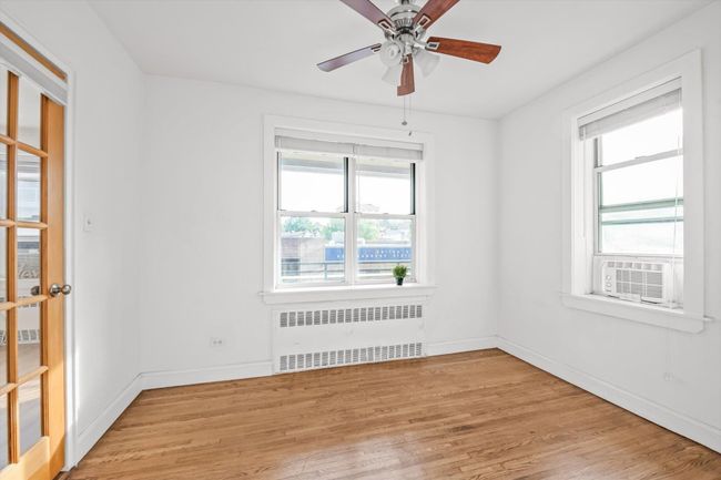 Empty room featuring radiator, light wood-type flooring, ceiling fan, and cooling unit | Image 9