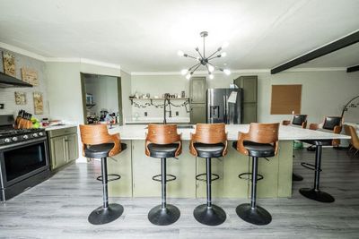 Kitchen with light hardwood / wood-style floors, appliances with stainless steel finishes, a notable chandelier, and a large island | Image 1