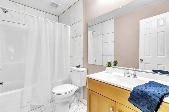 Full bathroom featuring shower / bath combination with curtain, visible vents, vanity, and toilet | Image 18