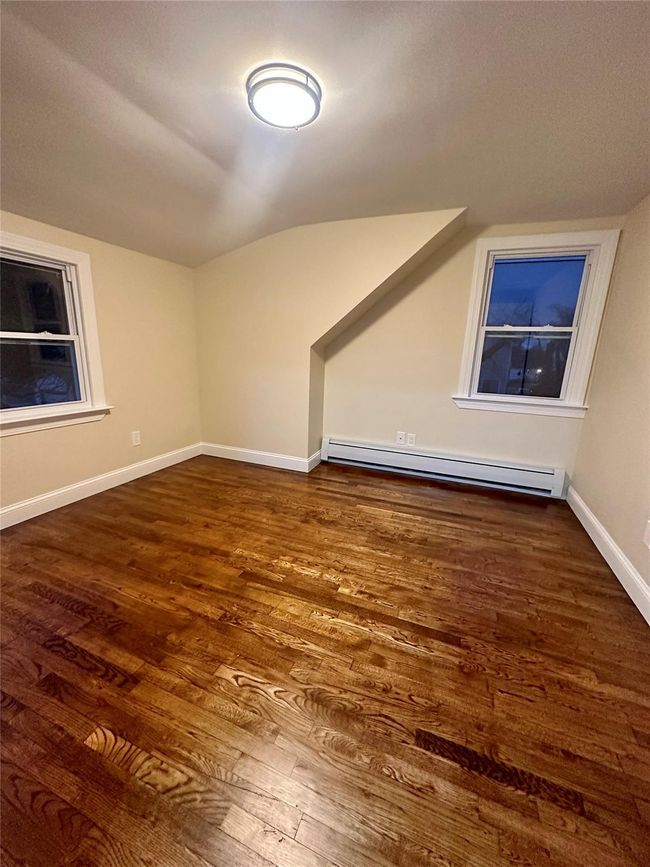 Bonus room with lofted ceiling, wood finished floors, a baseboard heating unit, and baseboards | Image 6