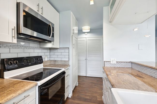 Kitchen featuring tasteful backsplash, electric stove, dark wood-style floors, stainless steel microwave, and white cabinetry | Image 10