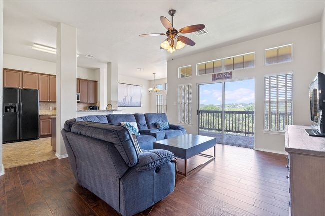 Living room with dark wood-style flooring, ceiling fan with notable chandelier, baseboards, and visible vents | Image 23
