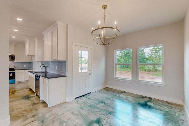 Kitchen featuring a chandelier, recessed lighting, tasteful backsplash, white cabinets, and dark countertops | Image 20