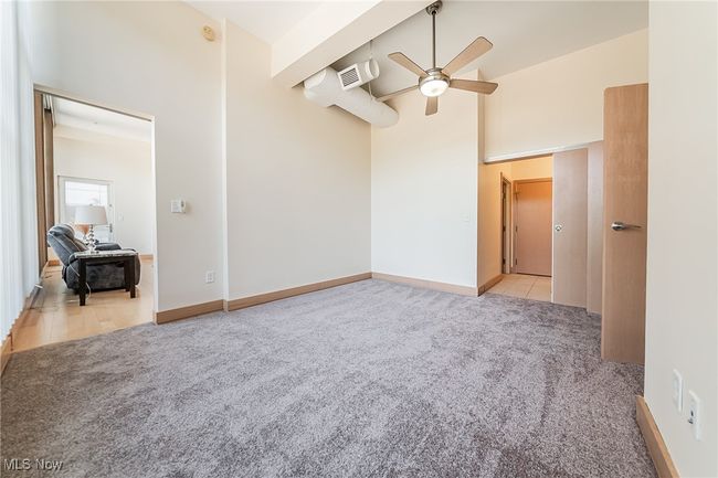 Bedroom featuring high ceiling, light carpet, walk-in closet, ceiling fan, and bathroom access. | Image 29
