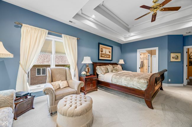 carpeted bedroom with visible vents, baseboards, ceiling fan, and a tray ceiling | Image 51