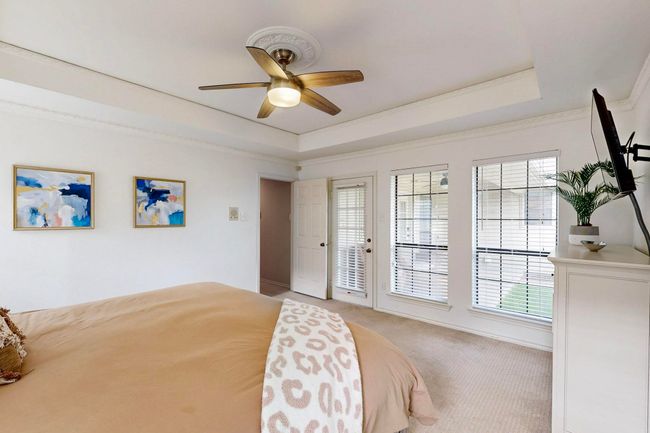 Carpeted bedroom featuring a tray ceiling, ornamental molding, and a ceiling fan | Image 18