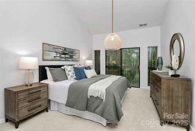 Expansive primary suite with vaulted ceilings, statement light fixture, plush carpeting and private patio with serene water views. | Image 12