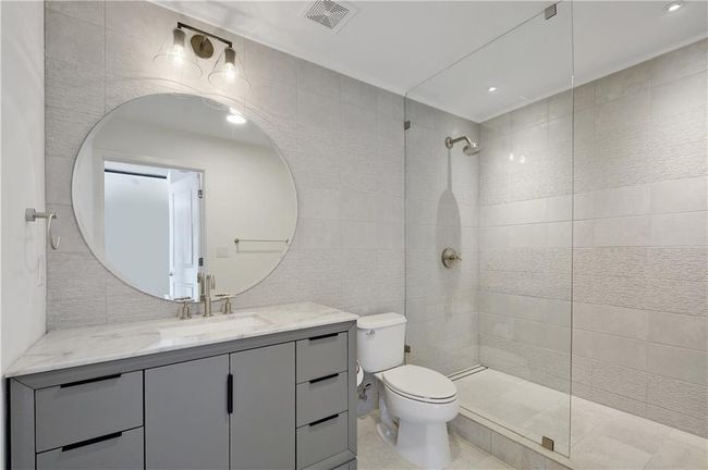 Bathroom featuring tile walls, visible vents, toilet, vanity, and a walk in shower | Image 15