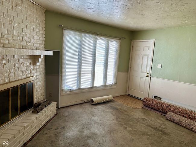 unfurnished living room with a fireplace, a textured ceiling, a wealth of natural light, and a wainscoted wall | Image 17