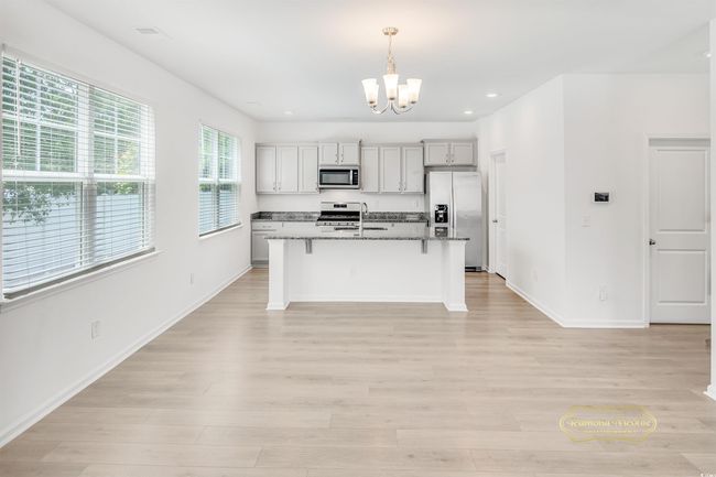 Kitchen featuring stainless steel appliances, a chandelier, a kitchen breakfast bar, a center island with sink, and light wood finished floors | Image 13